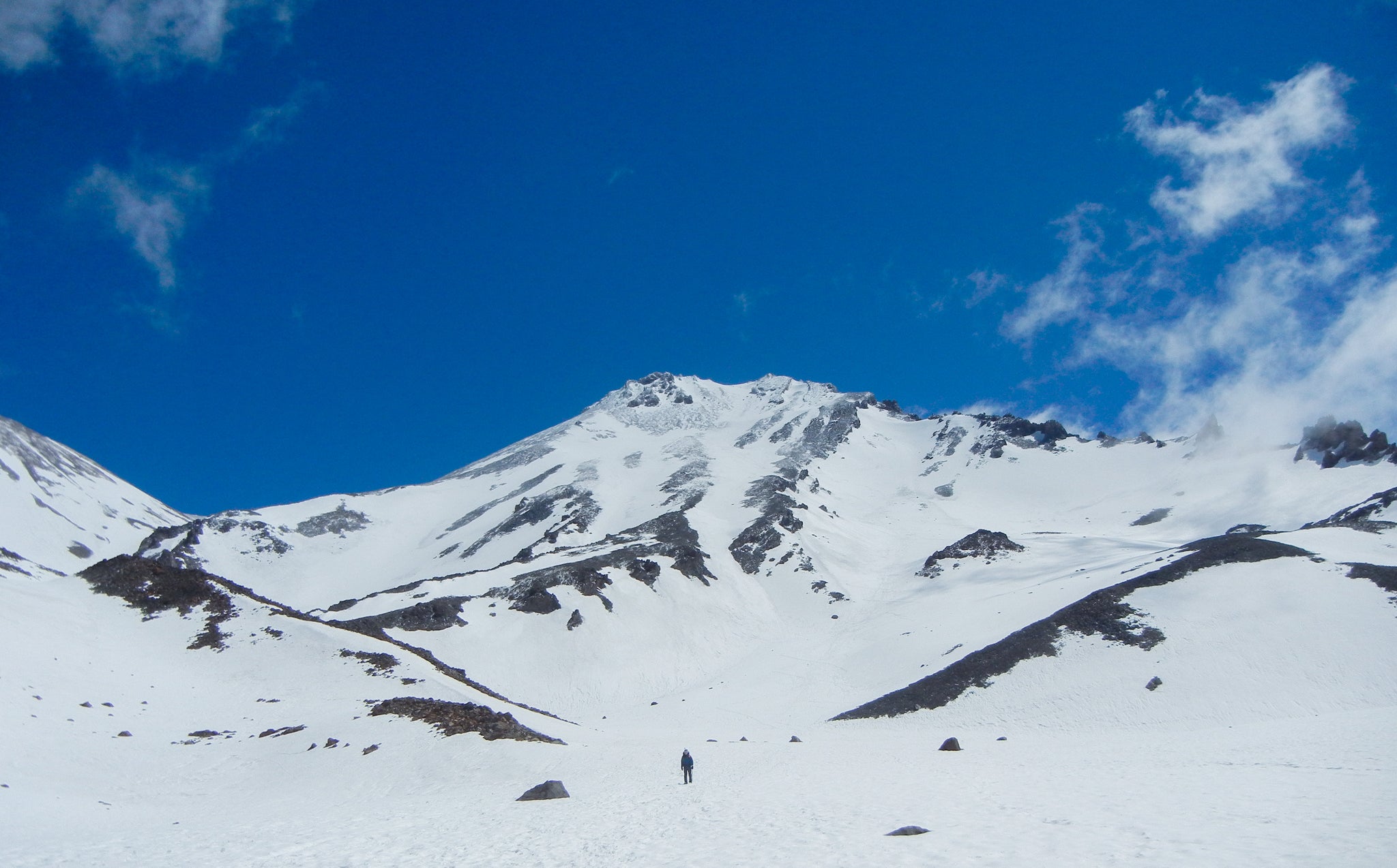a climber starting up the snow covered West Face of Mount Shasta during the middle of climbing season.