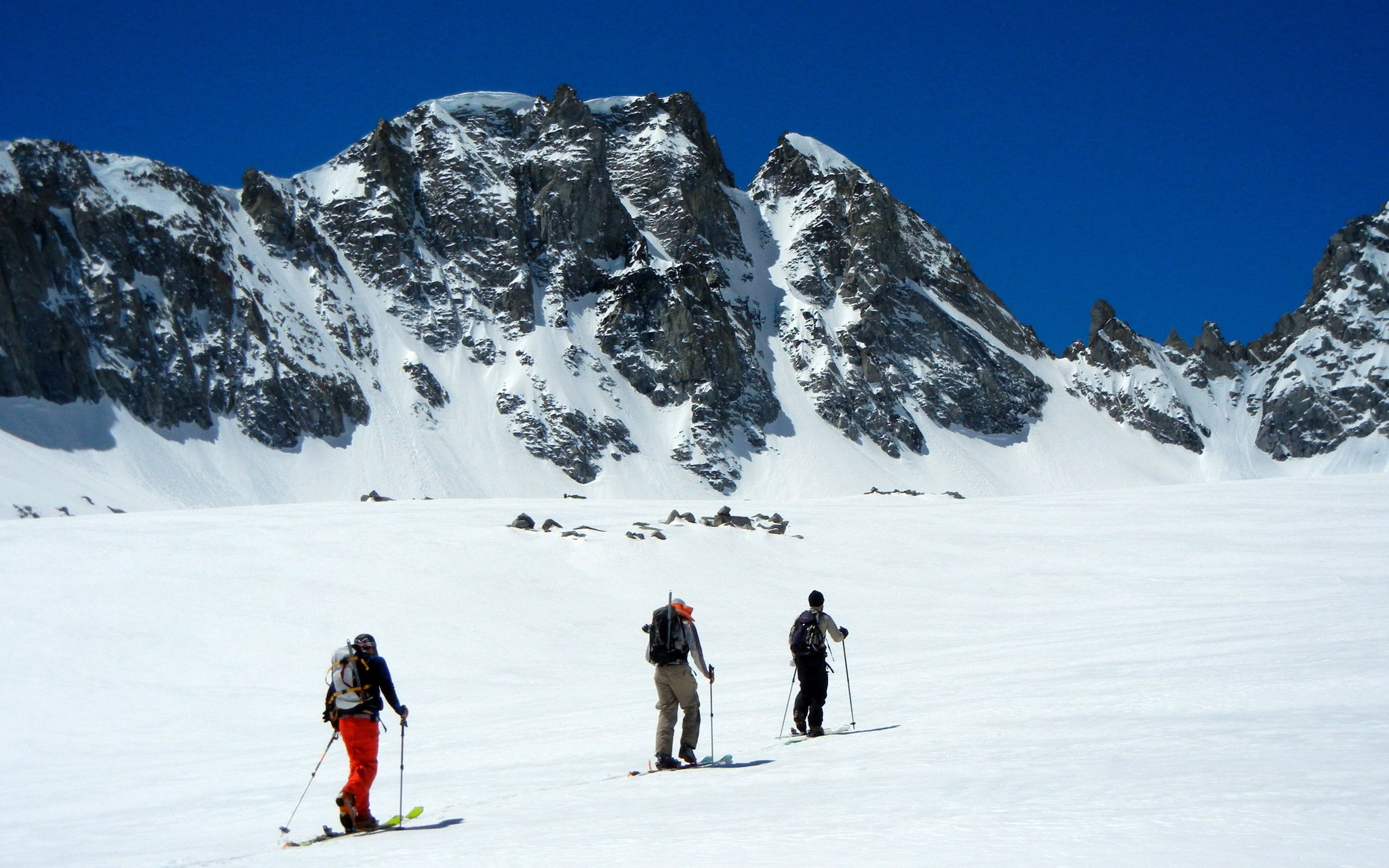 A team ski mountaineering across a snowfield on the way to ski Mount Johnson in the Eastern Sierra